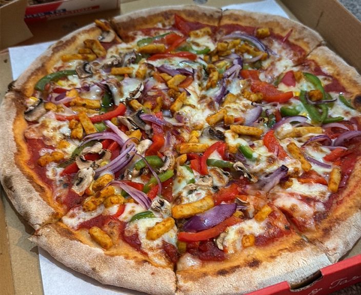 A vegetable and mixed-pepper pizza in a red box