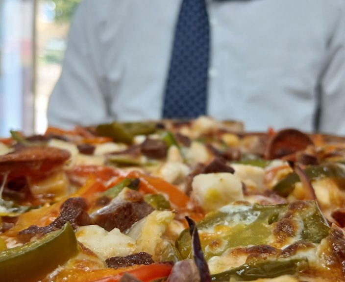 A close-up of a loaded pepper and chicken pizza