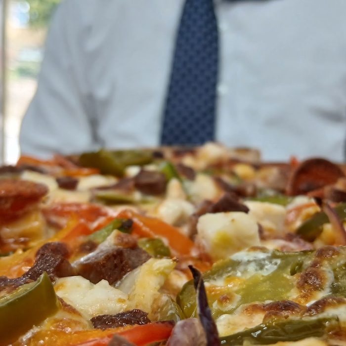 Pepper and chicken pizza held up close